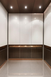 FSRT765 Интерьер лифта Levele-105 с нестандартными вставками в верхнюю панель; нижние панели из склеенной бронзы с темной патиной и нестандартным рисунком; панели поручней из плавленой бронзы с отделкой из каймового камня; прямоугольный поручень из атласн