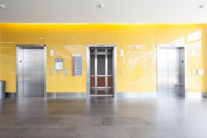 FSRT840 Интерьер лифта Levelc-2000n с верхними панелями из клееного алюминия с рисунком Чарльстон и натуральной патиной; нижние панели из шпона американского ореха; стойки и перила из нержавеющей стали, отделка из песчаника; круглые поручни в центре невро Forms-surfaces 